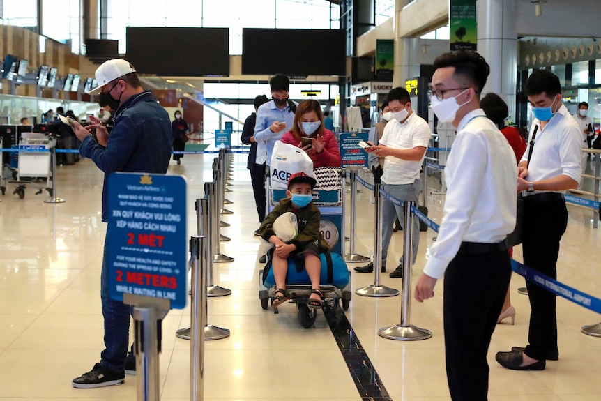 Passengers wait in line to check in at Hanoi airport, Vietnam.