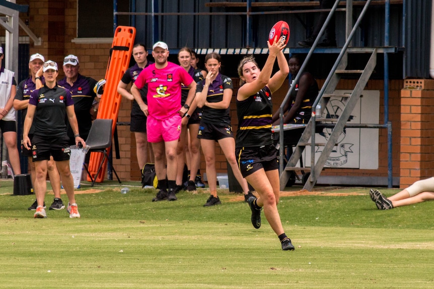 A girl wearing a black uniform marks a football