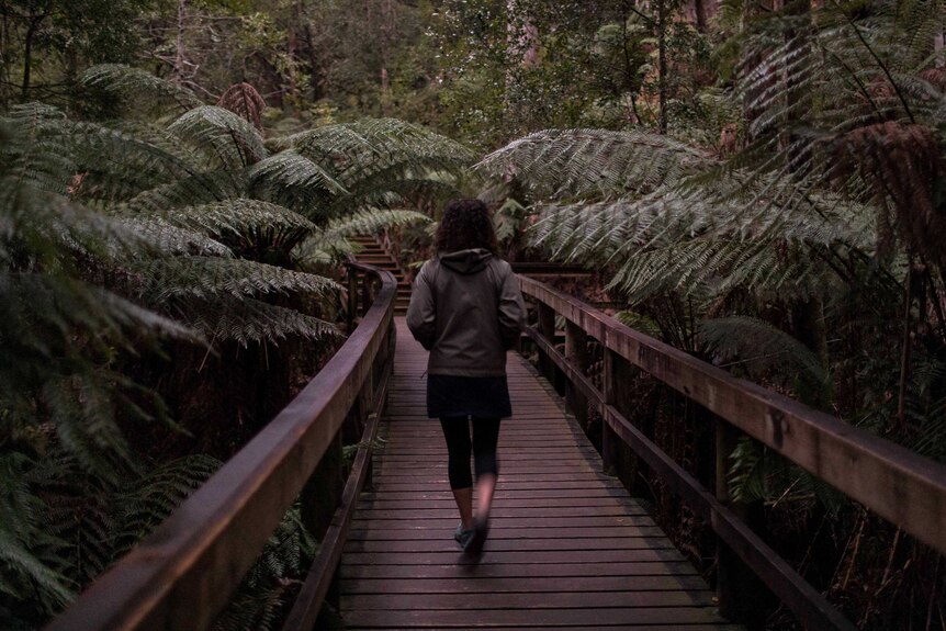 Woman walking in forest.