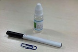 An e-cigarette sits next to a vial of nicotine