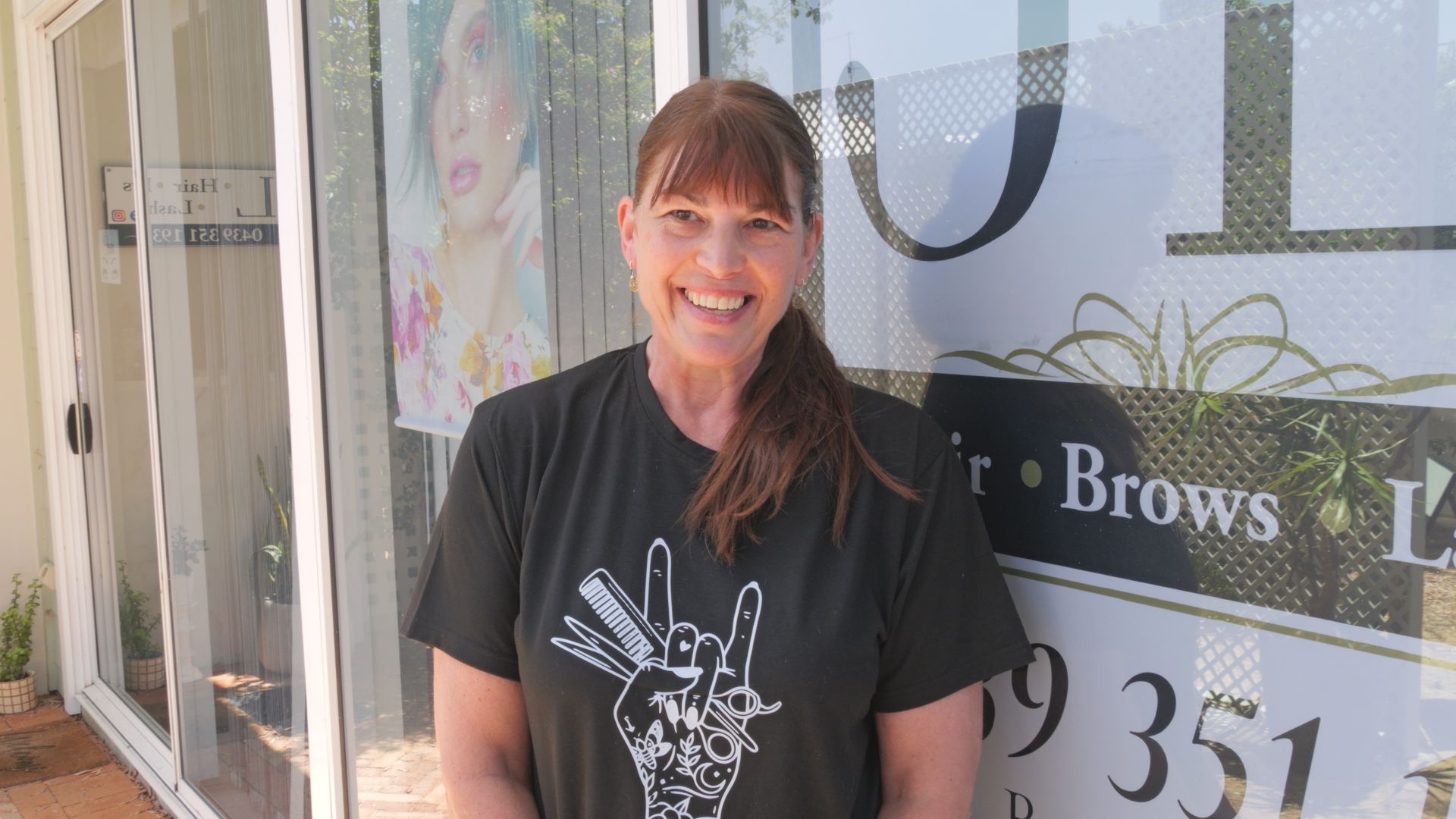Una mujer se encuentra frente a una peluquería.