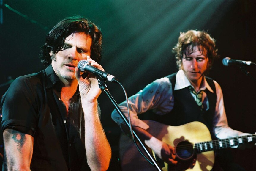 Tex Perkins performs on stage with Tim Rogers.