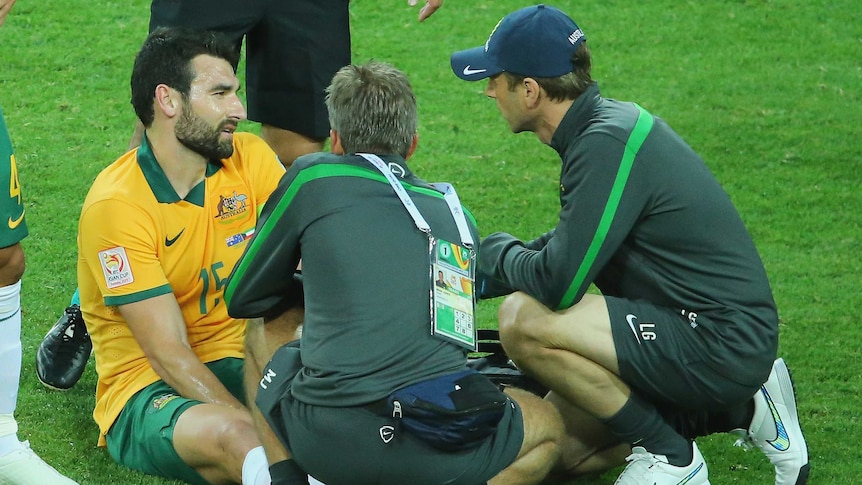 Socceroos captain Mile Jedinak is treated by medics after injuring himself at the Asian Cup.