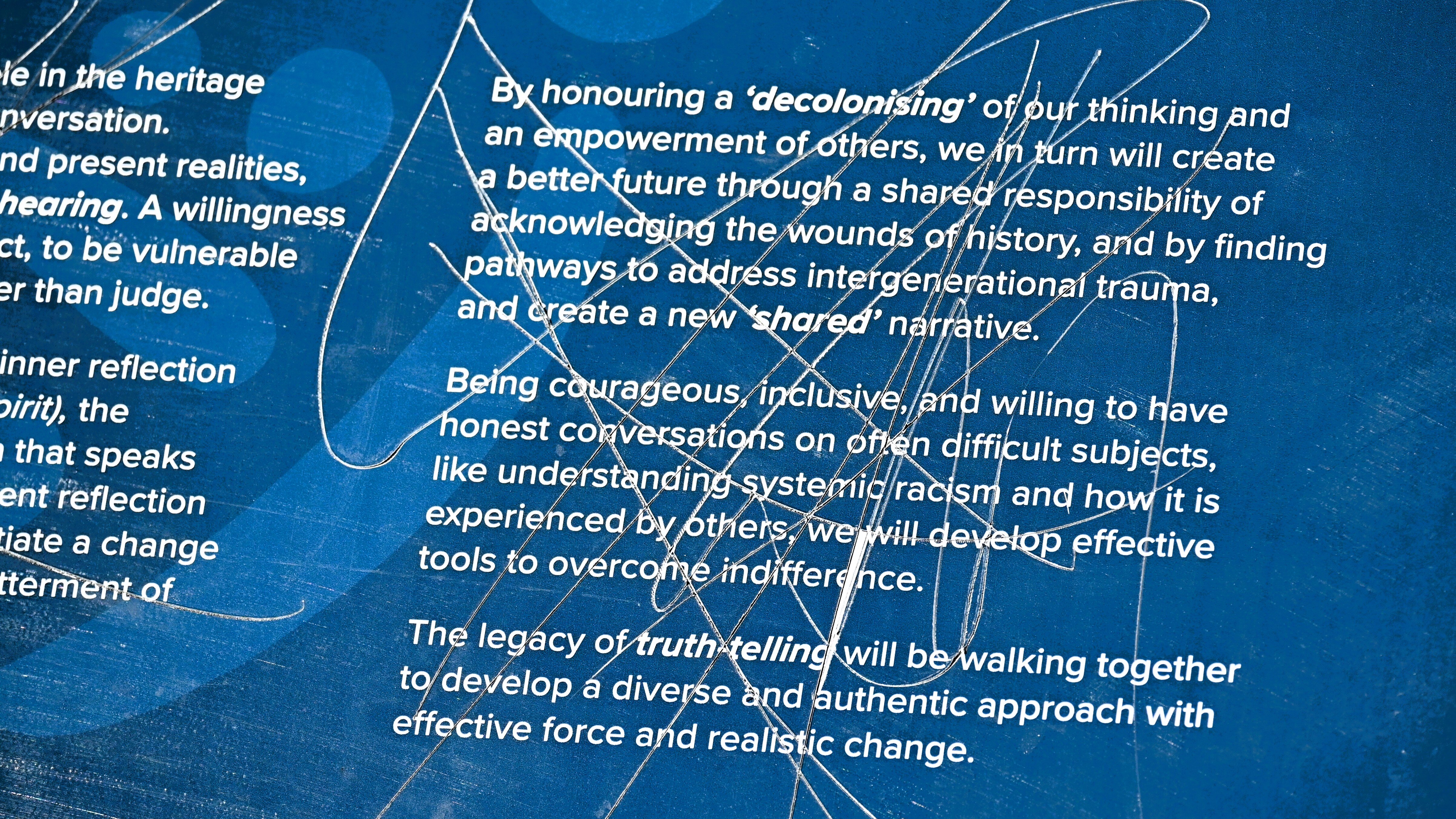Words on a sign that talk about the need for honest conversations about the past have been gouged and scratched through 