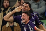 Xavier Coates and Jonah Pezet celebrate a Melbourne Storm try as Manly Sea Eagles' Reuben Garrick is on the ground.
