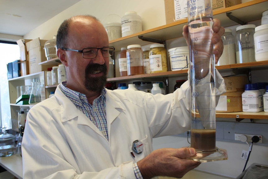 Grant Douglas examines a beaker used to test his Virtual Curtain method of filtration.