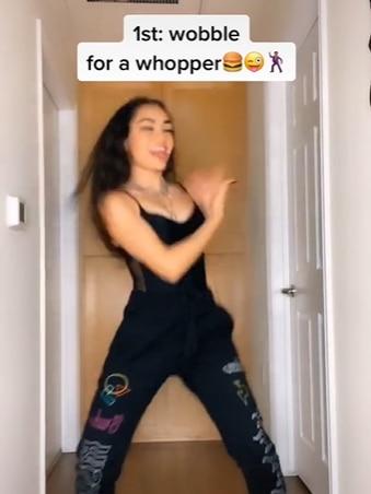 A woman dances in a TikTok video with a caption about Burger King.