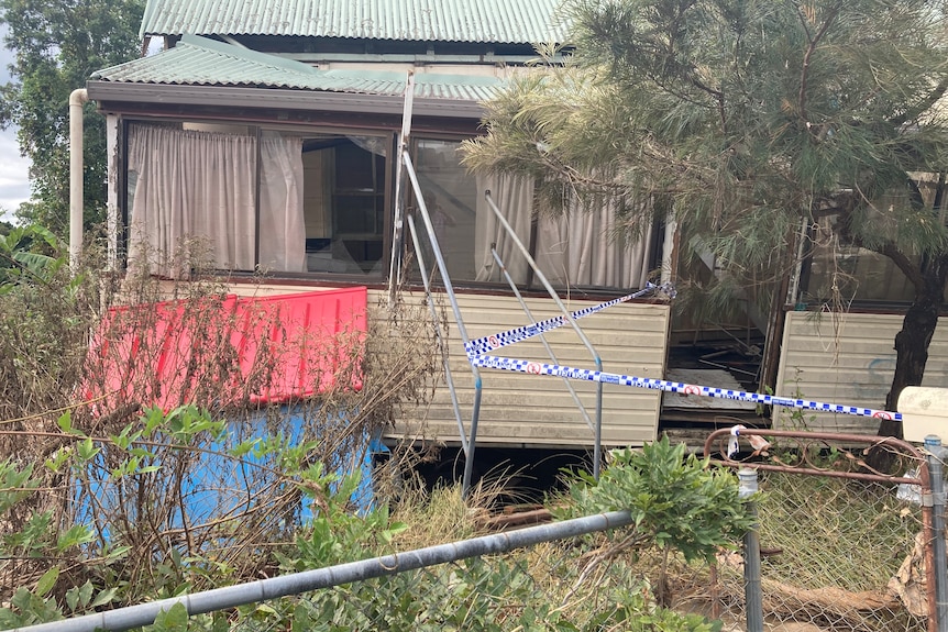 White weatherboard house blocked off by blue and white tape.