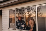 Greg and Lauren Newell looking out the window of their farm stay cottage. 