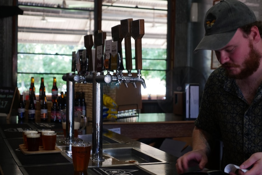 Man behind bar serving beers