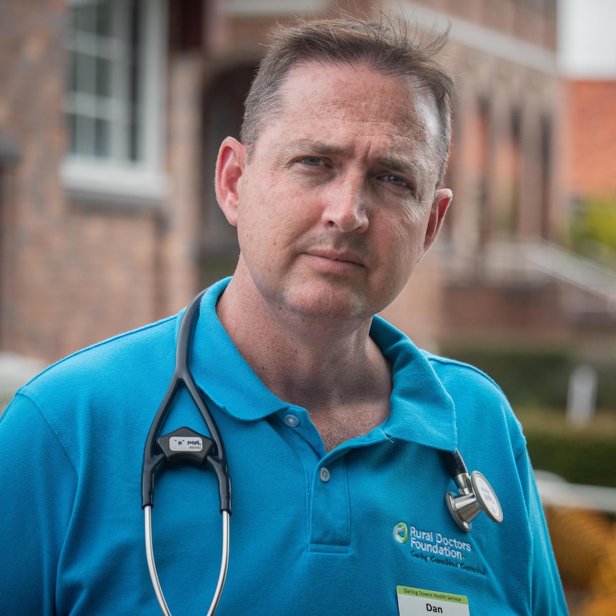 A man wearing a blue shirt with a stethoscope around his neck.
