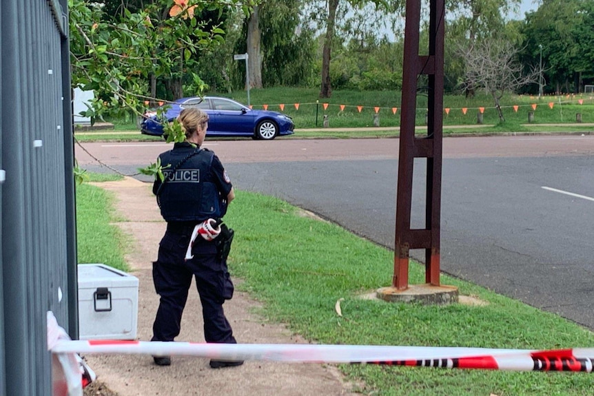 NT Police officer stands behind a taped off pathway in Jingili.