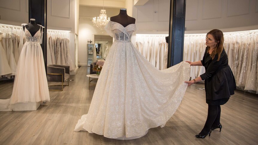 Patricia arranges a sparkling wedding gown on a mannequin