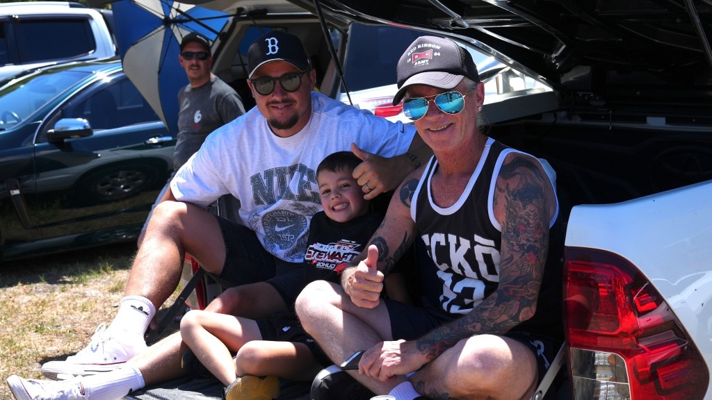 Dois adultos e uma criança participam de um festival de automóveis.