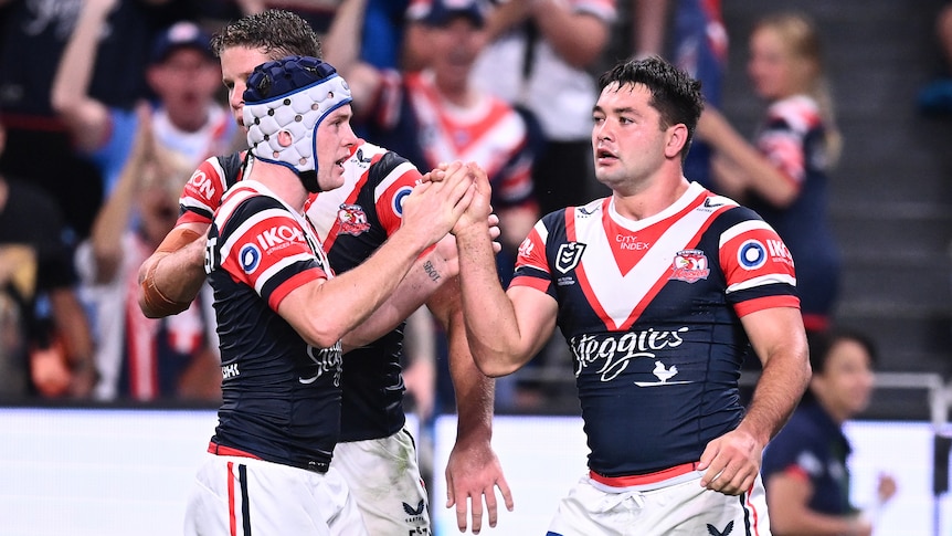 Three Sydney Roosters NRL players celebrate a try against the Rabbitohs.