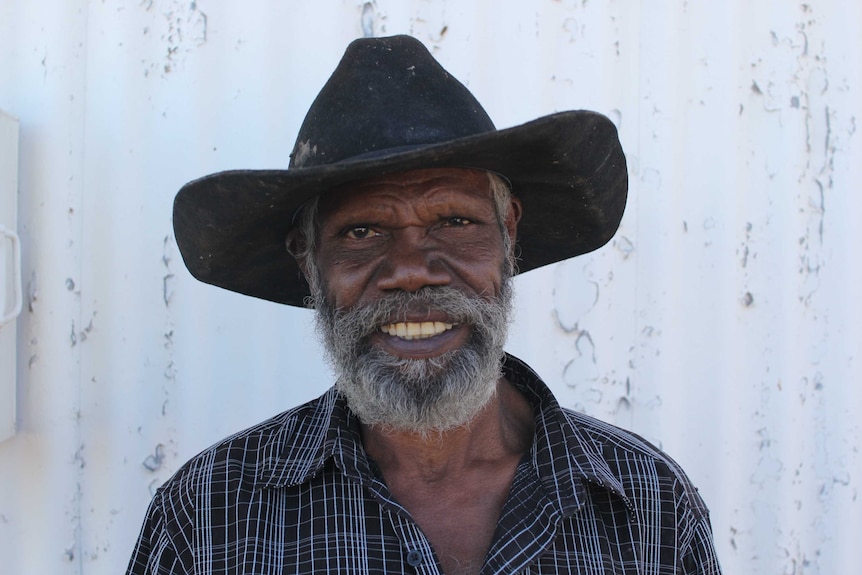 a man in a black hat in front of a white wall