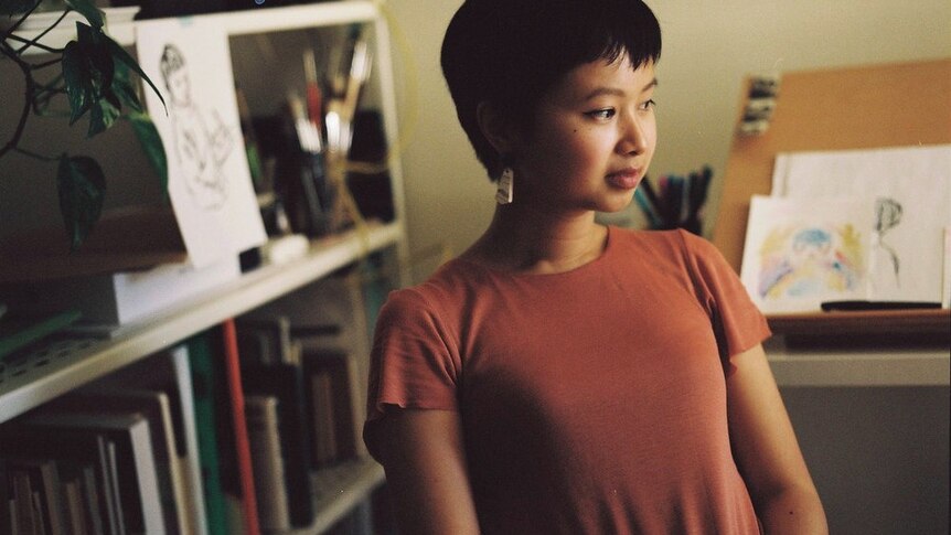 Melbourne artist Viet-My Bui sits in a red shirt.