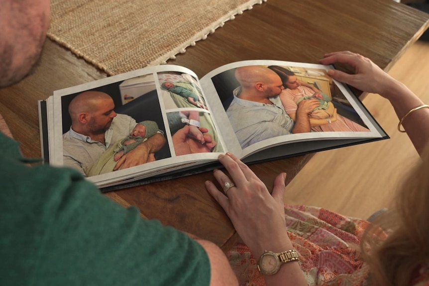 Photo album open with pictures of parents holding stillborn. 