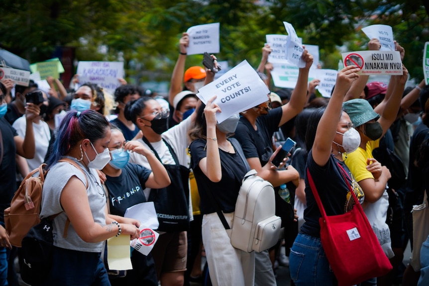 A group of people, mostly young women, wearing face masks and holding paper signs that read EVERY VOTE COUNTS