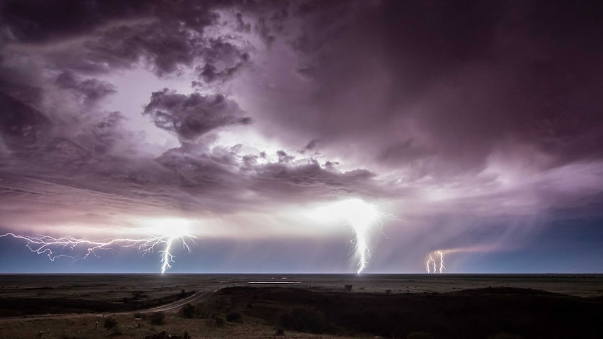 Three bolts of lightning descend form stormy skies across the Mundi Mundi plains near Silverton