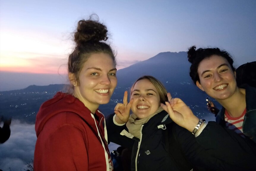 three ladies smiles towards camera with sunrise at the back