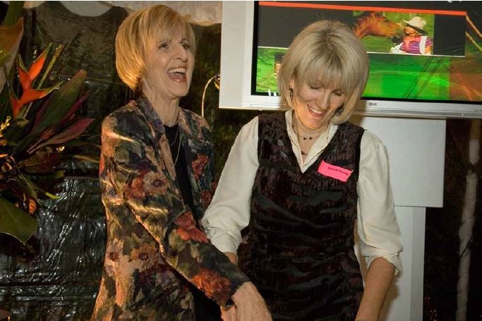 two women smile big cutting a large cake that reads Australian Story celebrating 10 years