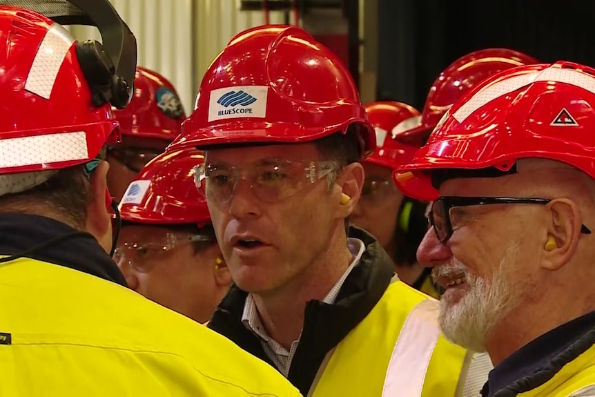 three men in headgear and protective clothing standing and talking