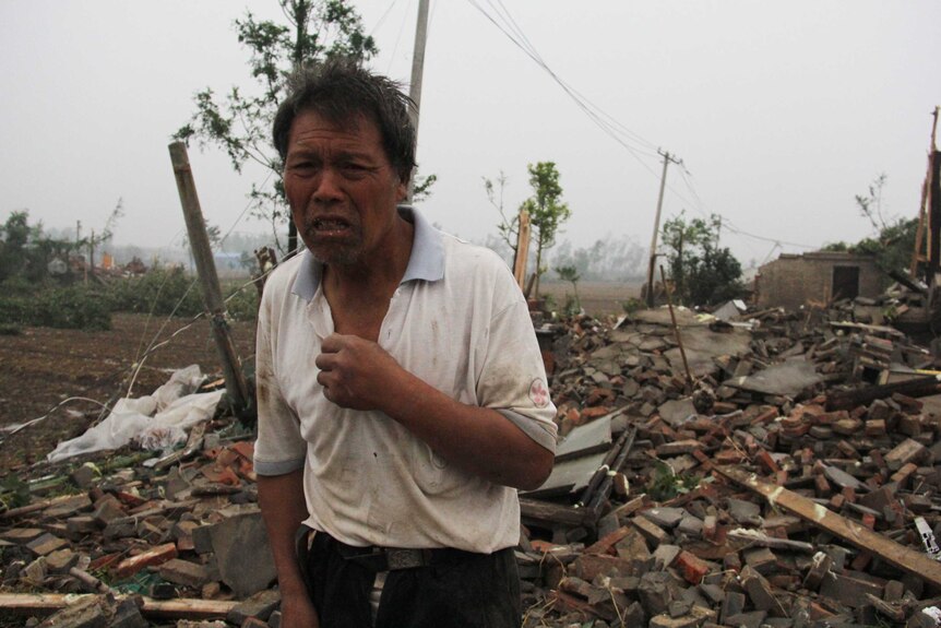 A man walks through the rubble of destroyed houses.