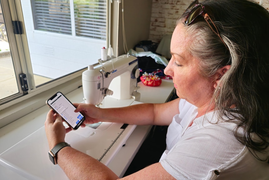 woman sits on her phone refreshing a website