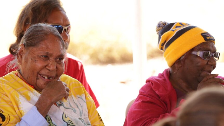 Two Indigenous women in the foreground watching a performance.
