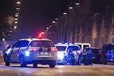Officers crouch behind police cars on a street in central Copenhagen.