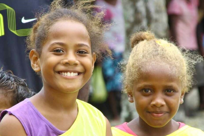 Two young Solomon Islands girls smile for the camera.