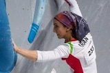 Climber Elnaz Rekabi hangs from climbing holds while competing in a bouldering comeptition.