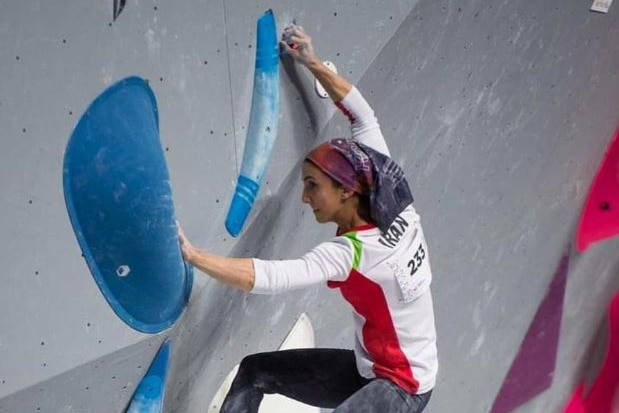 Climber Elnaz Rekabi hangs from climbing holds while competing in a bouldering comeptition.