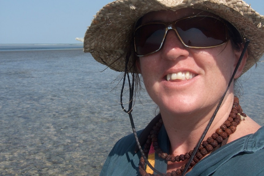 A selfie of a woman with sunglasses and a hat