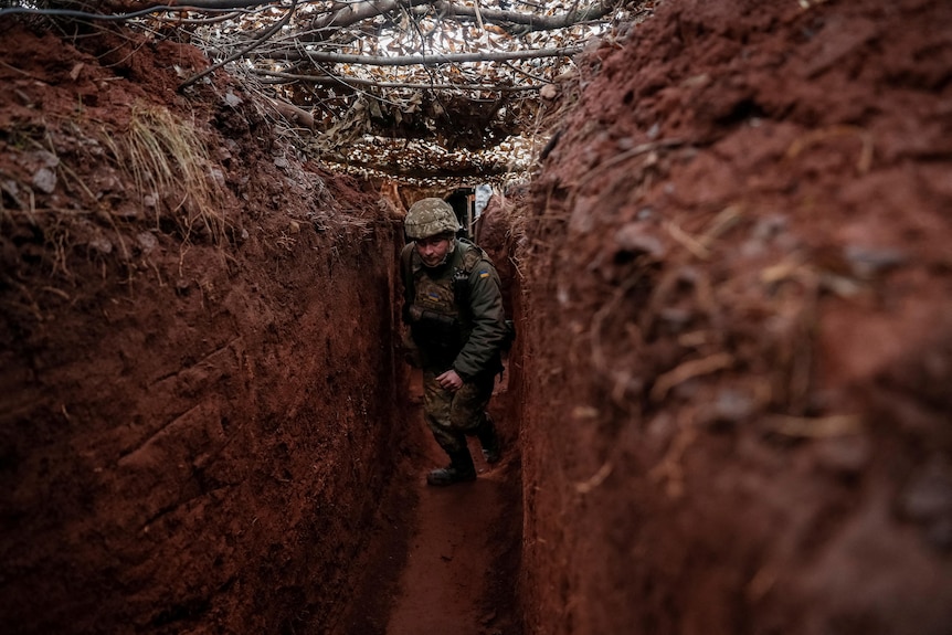 A soldier walks along a trench.