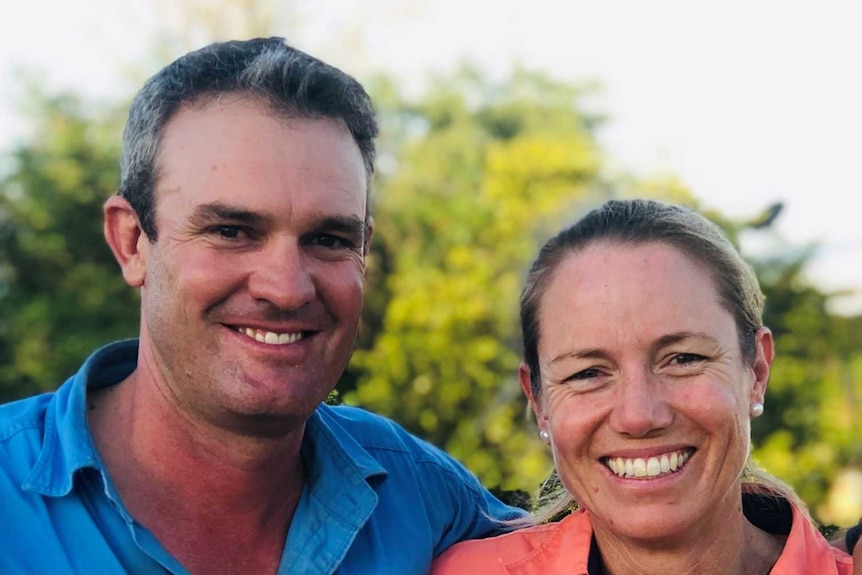 A man and a woman in front of a homestead.