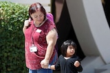 A young girl holds a woman's hand