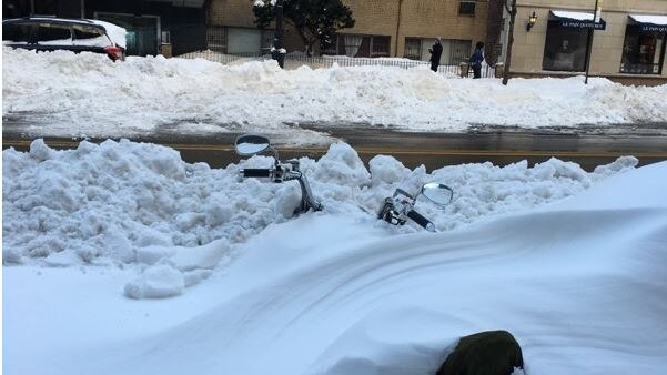 Part of the handlebar and seat of a motorbike sticks out from snow