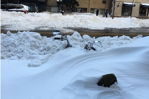 Part of the handlebar and seat of a motorbike sticks out from snow