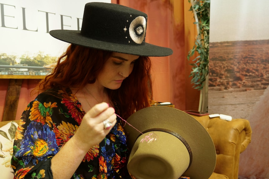 Jules Holland embroidering a hat and wearing another hat.