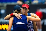 Ajla Tomljanovic hugs Iga Swiatek over the net after retiring from their tennis match at the Ostrava Open.