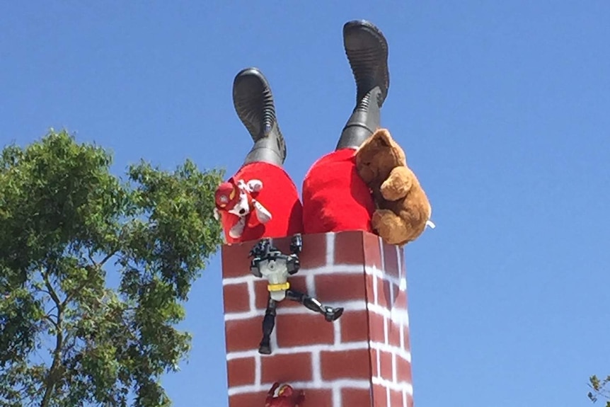 Only Santa's boots and red trousers can be seen sticking out of a chimney