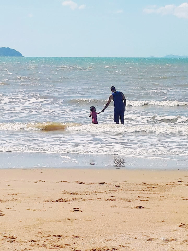 Man with little girl in the water at the beach