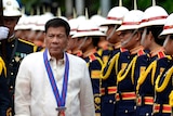 Philippine President Rodrigo Duterte walks past honour guards.