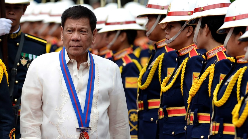 Philippine President Rodrigo Duterte walks past honour guards.