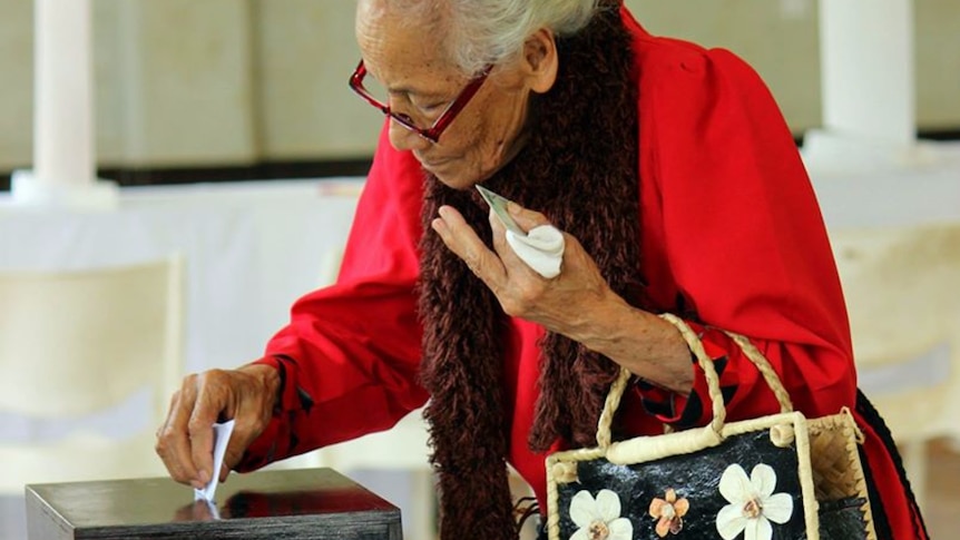 elderly woman posting her vote in the ballot box at the Tongan election