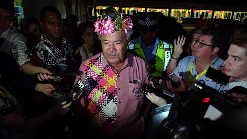 Tuvalu's Prime Minister Enele Sopoaga walks thorough a crowd of press with their microphones pointed at him