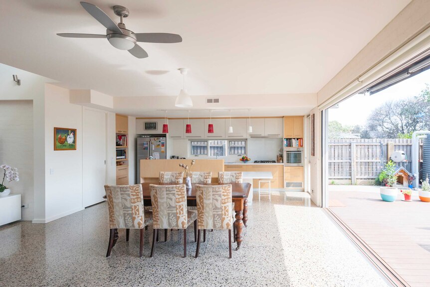 A modern open-plan kitchen dining area opening out onto a deck