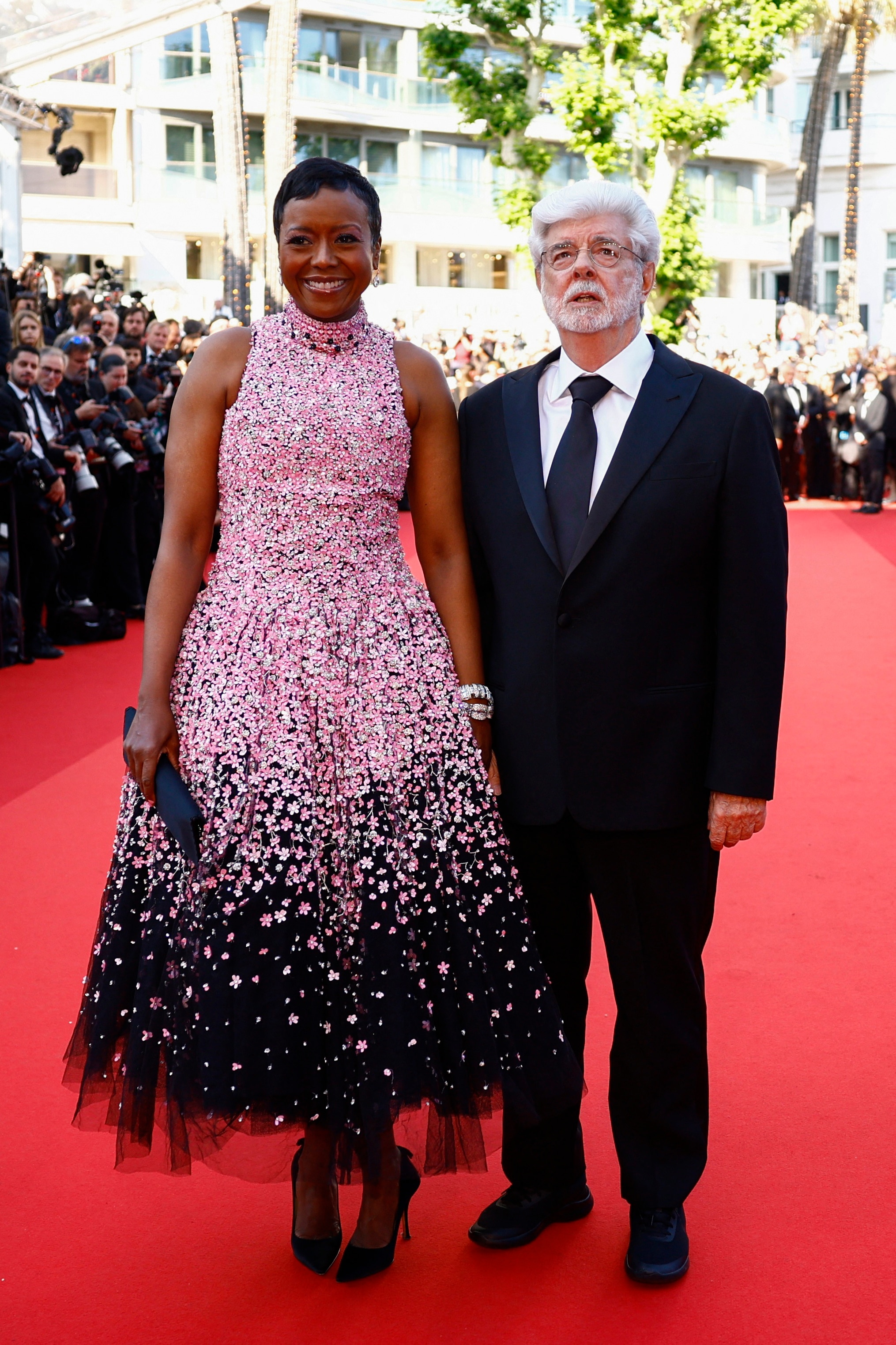 George Lucas wearing a black suit and Mellody Hobson in a pink sparkly high-necked dress which transitions into a black skirt